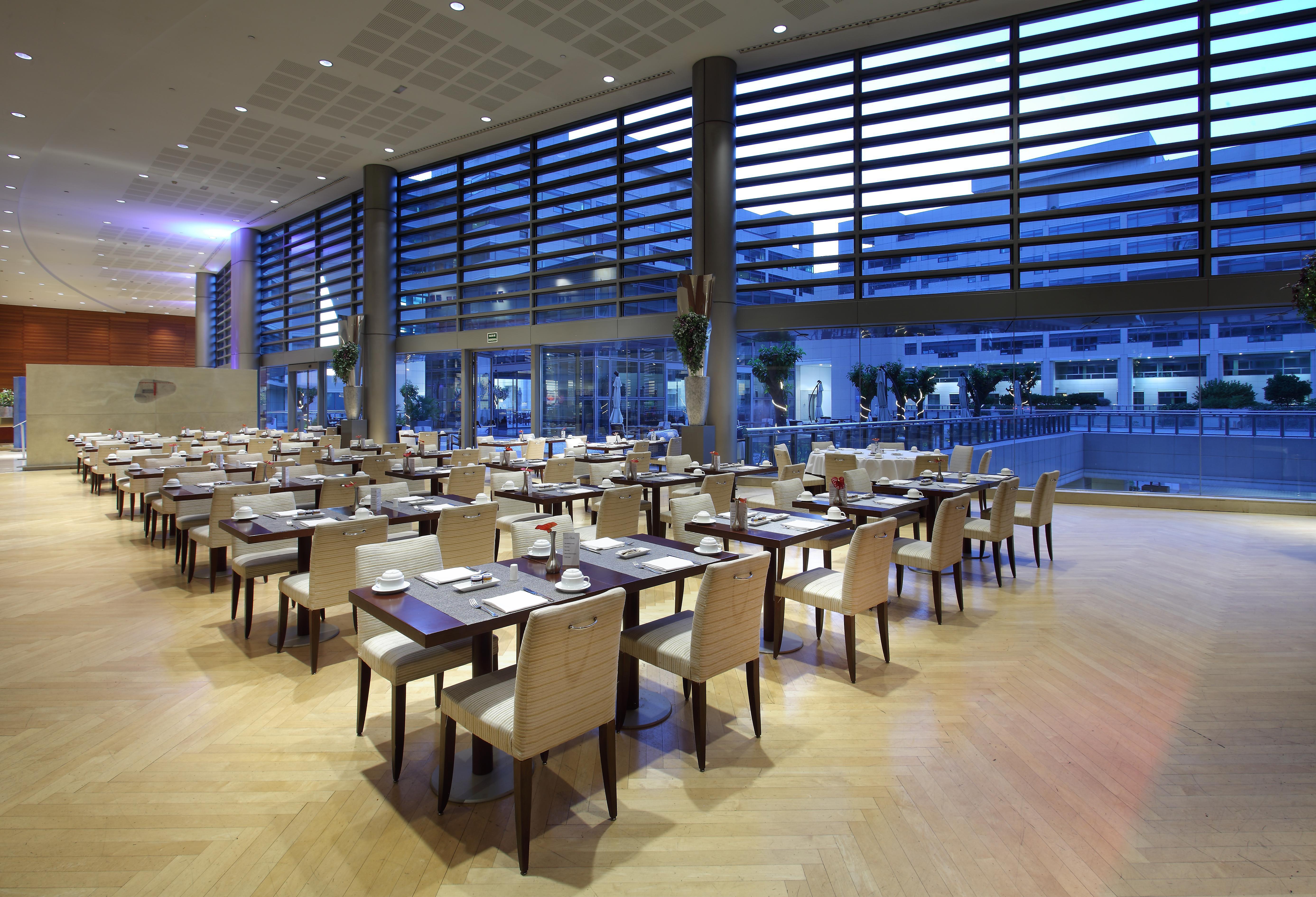فندق يوروستارز غراند مارينا جي إل برشلونة المظهر الخارجي الصورة The photo depicts a modern restaurant interior. It features a spacious dining area with several tables arranged neatly throughout. Each table is set with plates and utensils, suggesting readiness for guests. Large windows allow natural light to fill 